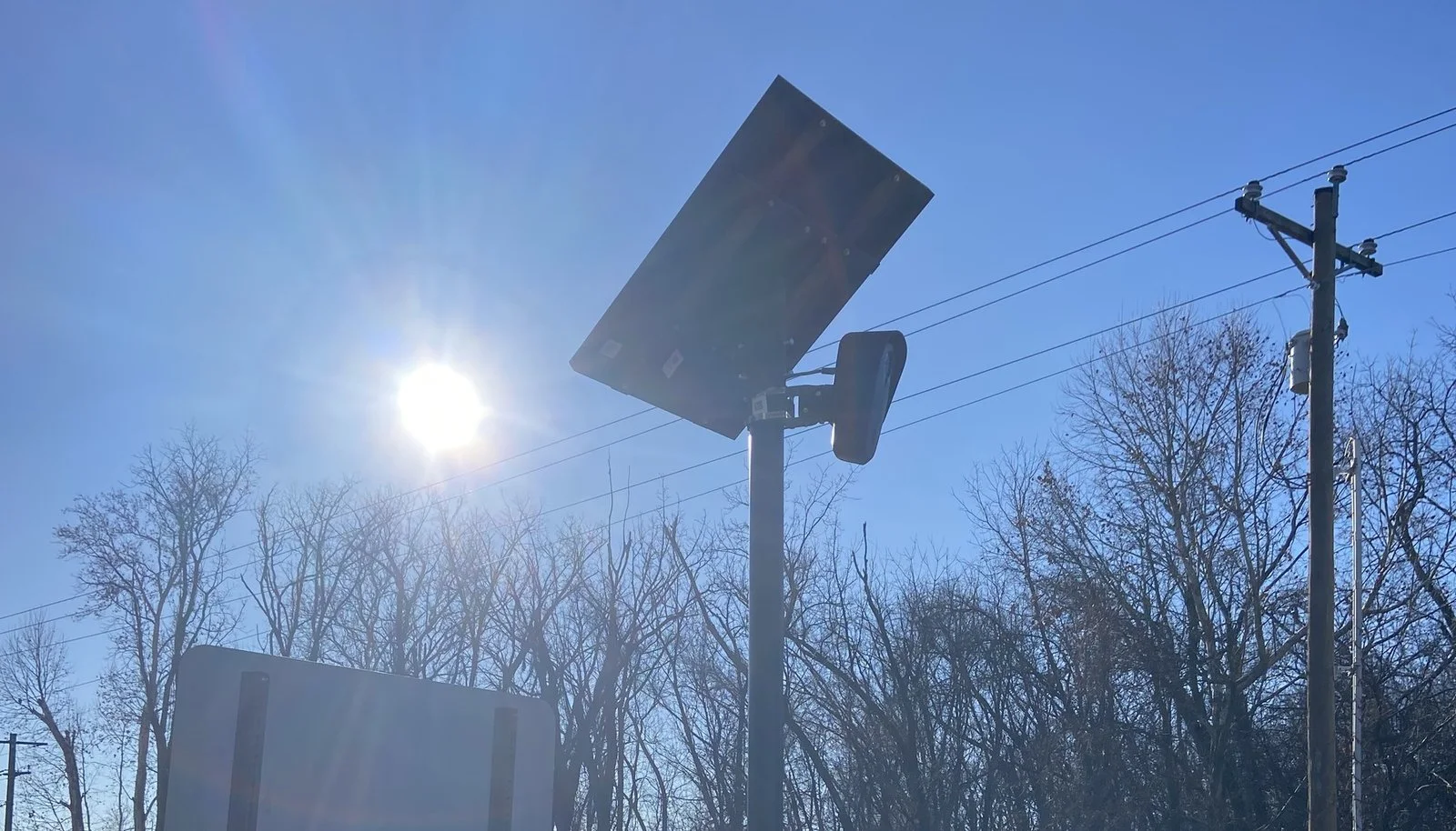 A solar-powered Flock Safety automated license plate reader mounted beside a road